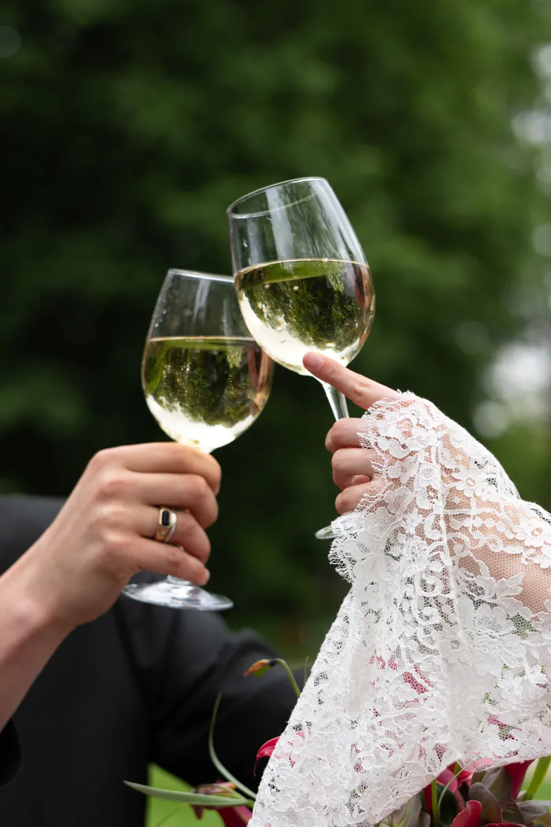 Toast pary młodej, kieliszki wina i koronkowy rękaw sukni