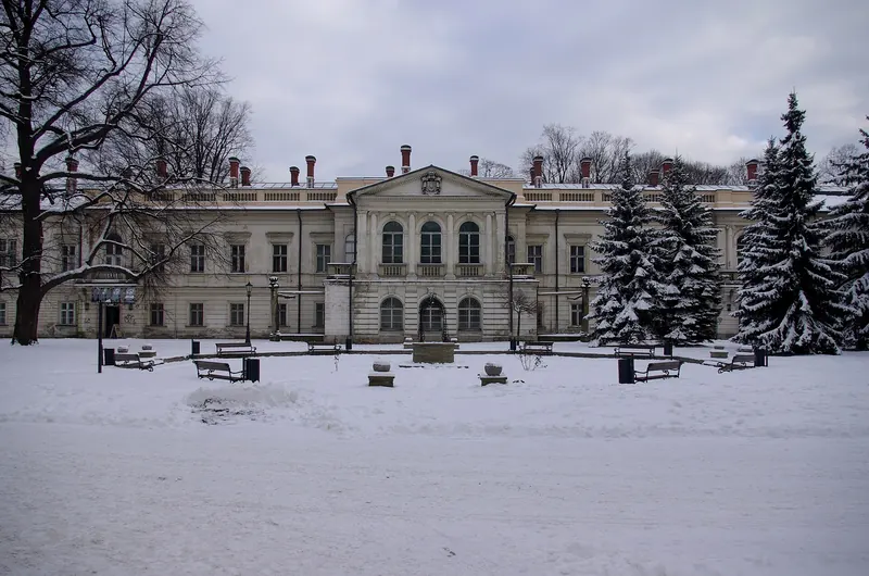Pałac Habsburgów w Żywcu w śniegu, przed nim ośnieżone świerki i ławki